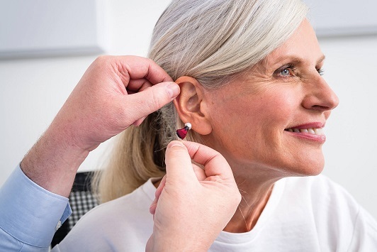 Eine ältere Frau erhält ein Hörgerät, um ihr Hörvermögen im Alltag zu verbessern.